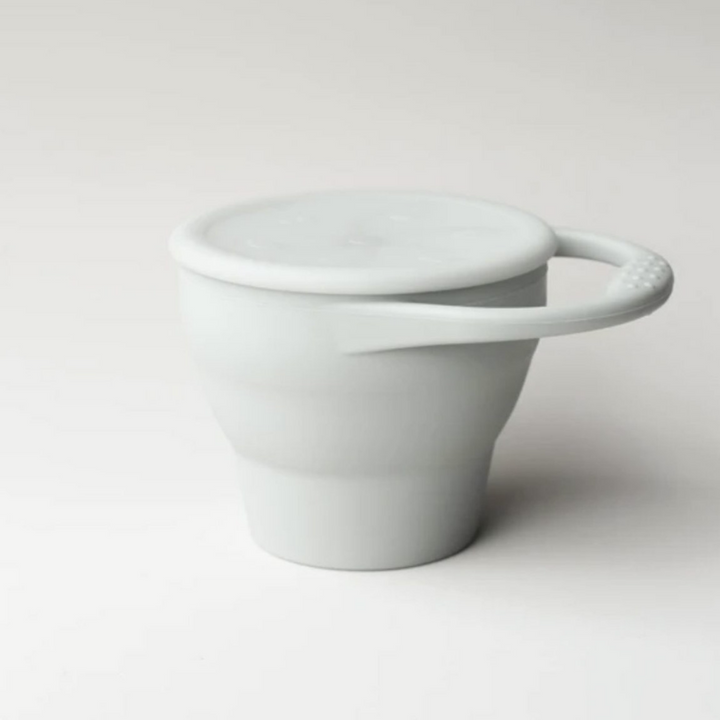 Toddler foldable silicone snack cup with hand in taupe grey