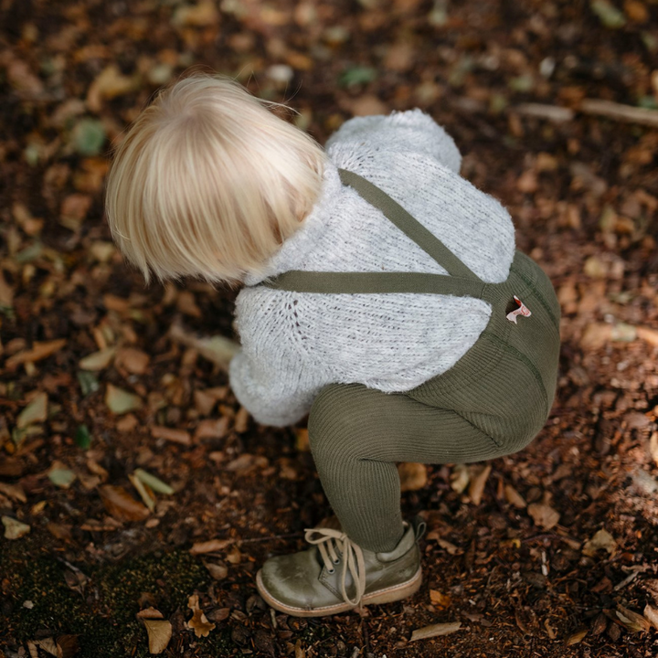 Blonde toddler boy wearing Silly Silas olive green cotton ribbed tights with braces/suspenders