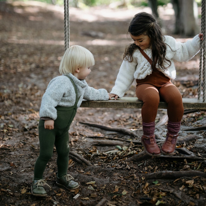 Blonde toddler boy wearing Silly Silas olive green cotton ribbed tights with braces/suspenders