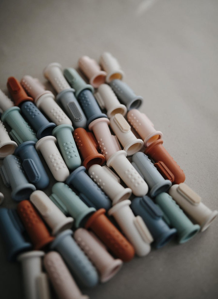 BLue, green, pink and beige finger toothbrushes lined up