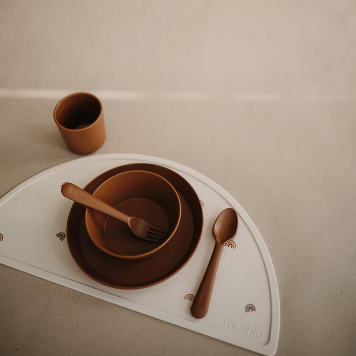 Caramel brown kids plate bowl, cup, fork and spoon on rainbow silicone placemat