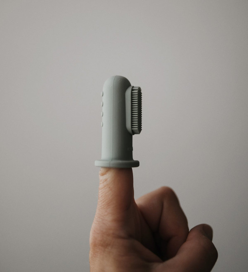 Green finger toothbrush baby on index finger