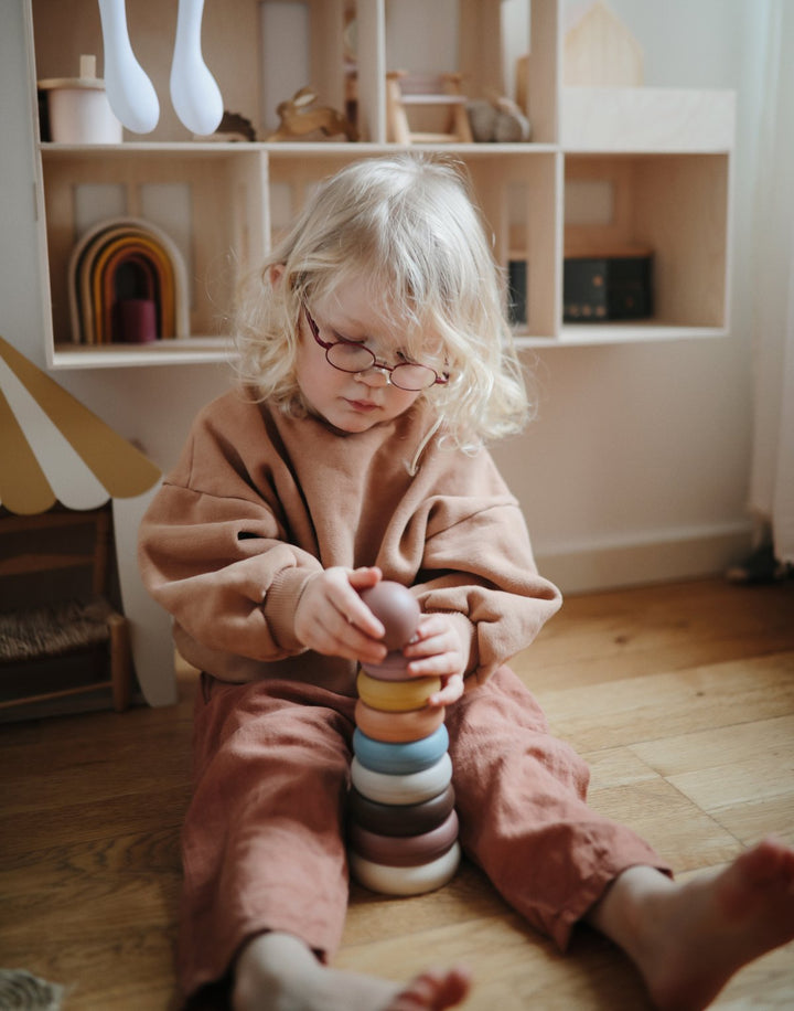 Girl playing with Mushie original ring stacking tower toy