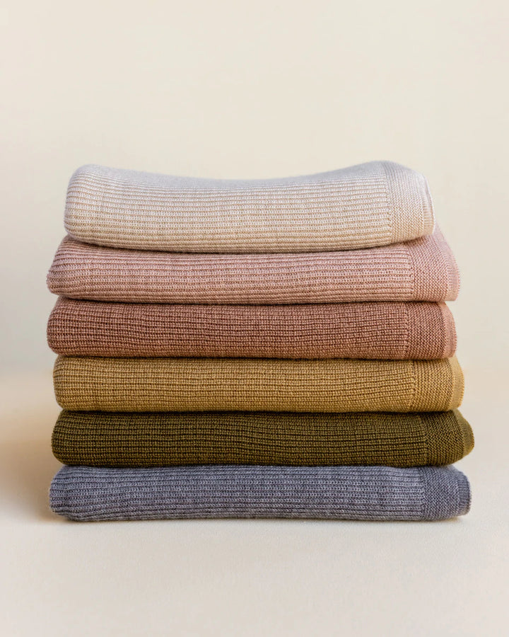 Hvid knitwear stack of folded blankets rib merino wool in grey ochre, mustard, neutral sand white apricot peach