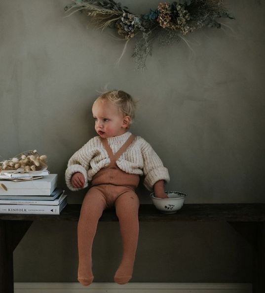 Blonde toddler wearing Silly Silas light brown rib tights with braces and white knit jumper