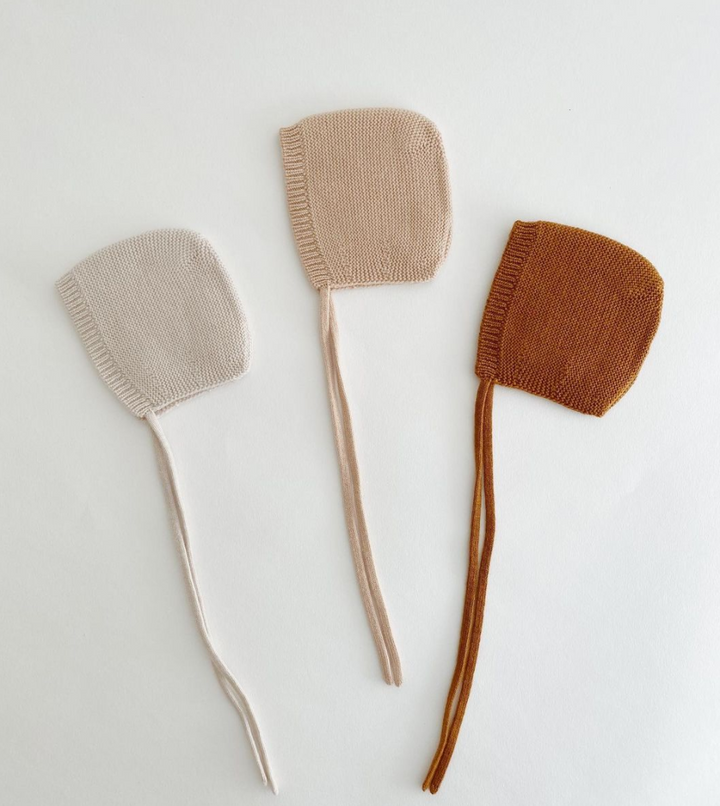 Flat lay of three bonnets in white beige sand rust brown neutral