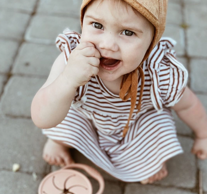 Toddler girl eating snacks from pink coral silicone snack cup