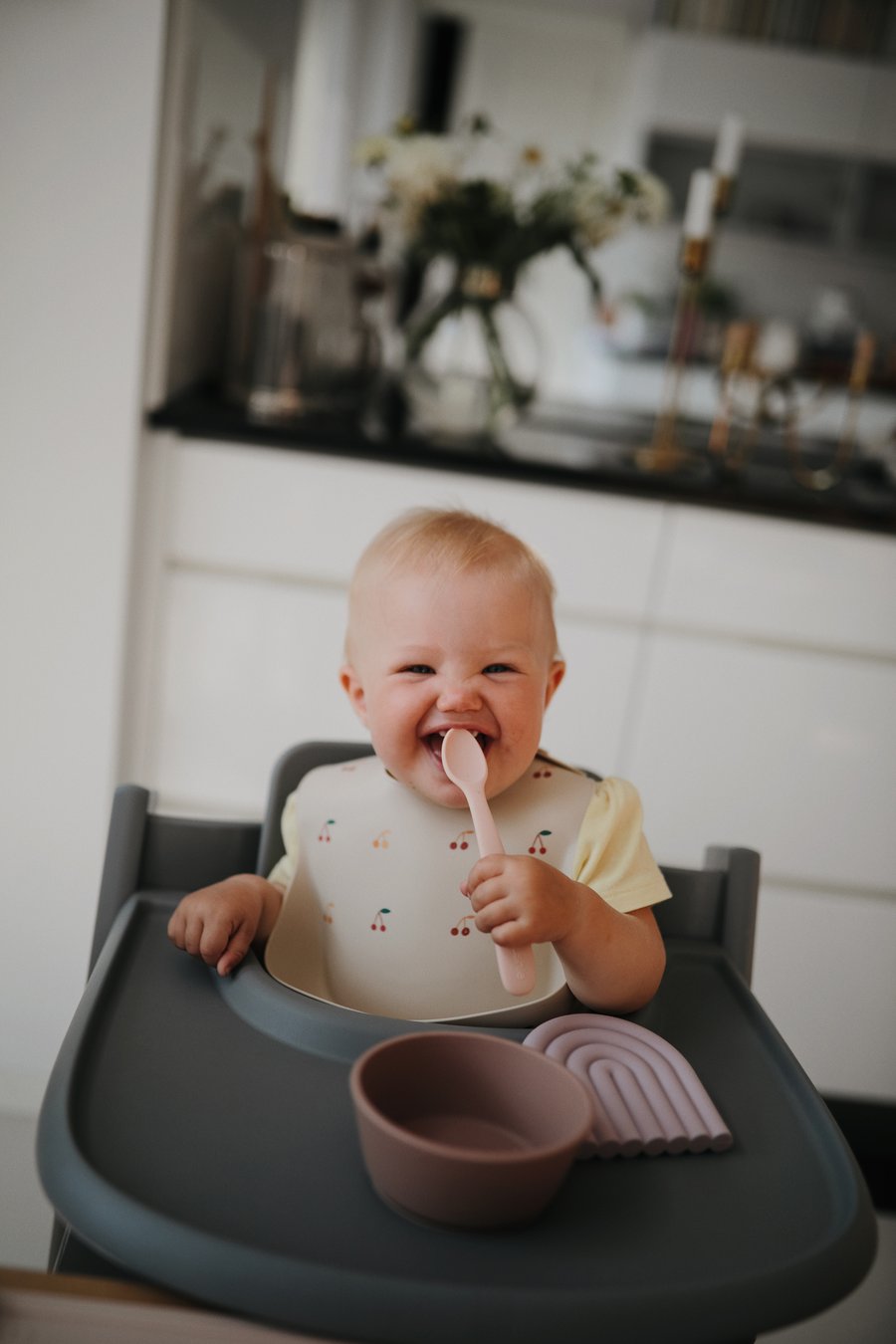 Baby in highchair eating from bowl with baby spoon
