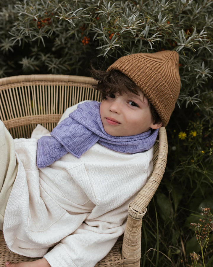 Toddler boy lounging on park bench wearing brown Hvid Knitwear organic merino wool beanie